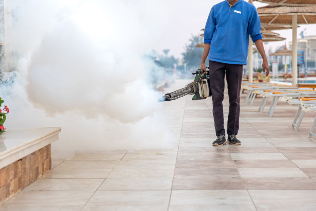 A worker using fogging to disinfect and sanitize an outdoor area.