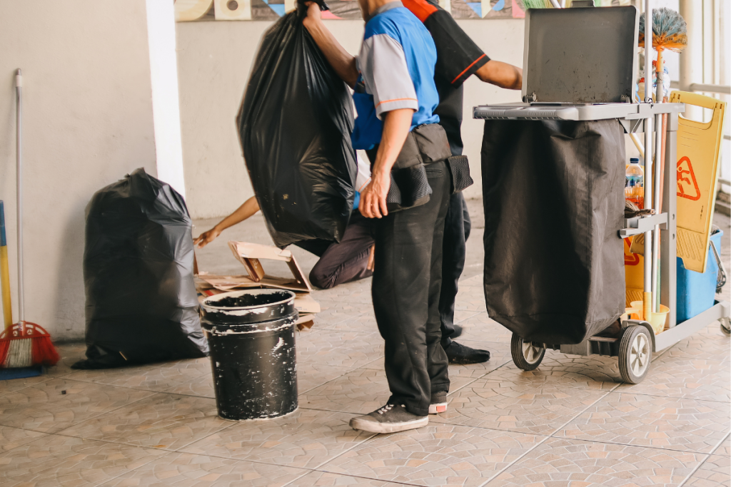 Three janitors cleaning commercial space with garbage bags and bucket