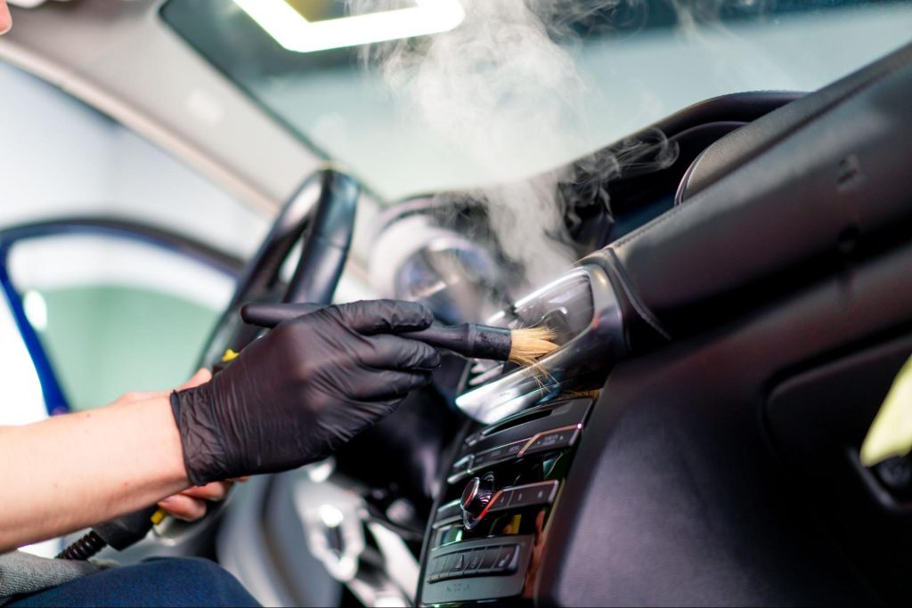 Professional cleaning interior of luxury car to prevent slush or salt buildup from winter conditions