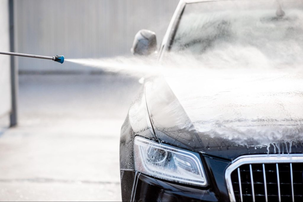 Pressure washer being used to rinse down car in winter