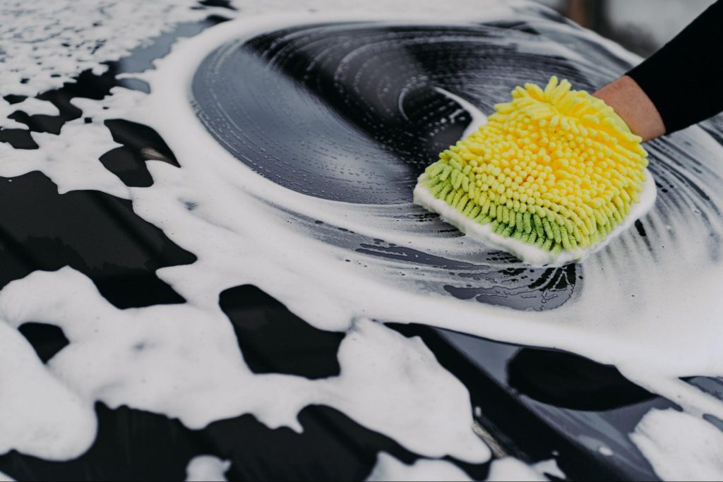 Man using sponge to wash car carefully
