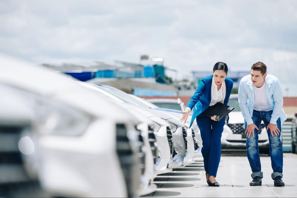 Manager of auto dealership showing cars to client on clean lot