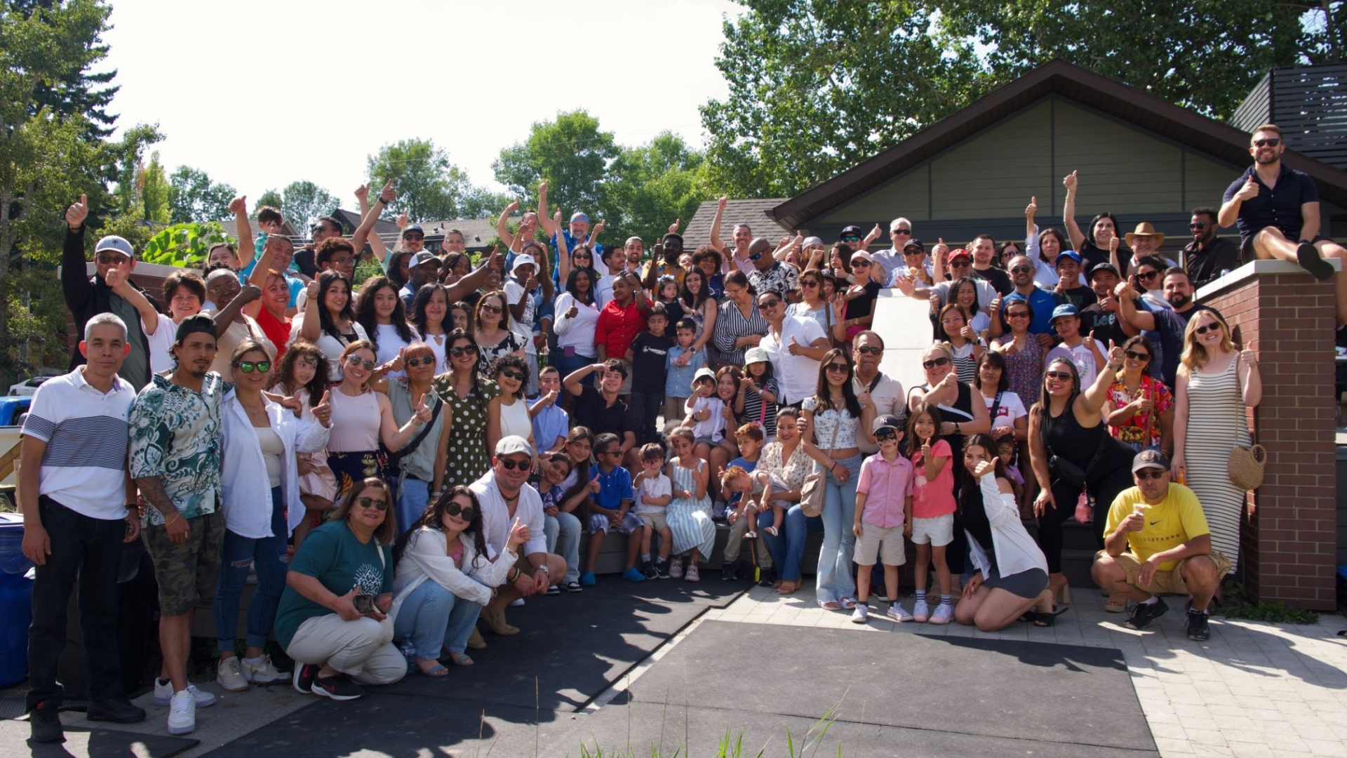 A large group of Picture Perfect Cleaning employees and their families gathered outdoors for the annual summer staff party, celebrating with smiles and raised hands.
