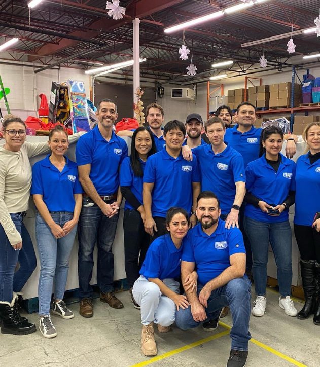 The PPC team poses in a warehouse surrounded by gifts while volunteering at The Magic of Christmas charity event in Calgary.