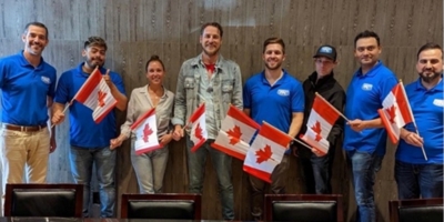 Aaron Graham, COO of Picture Perfect Cleaning, celebrates becoming a Canadian citizen with PPC team members holding Canadian flags.