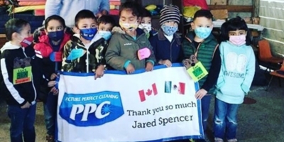 Group of young Mexican students holding a Picture Perfect Cleaning banner, thanking Jared Spencer for supporting a sustainability and composting education program.